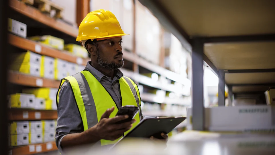 Warehouse colleague checking stock beside storage shelves